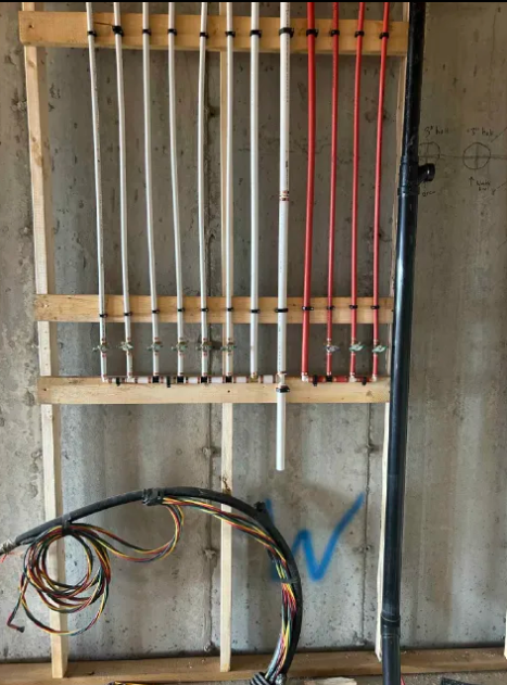 Professional PEX pipe installation along a concrete wall